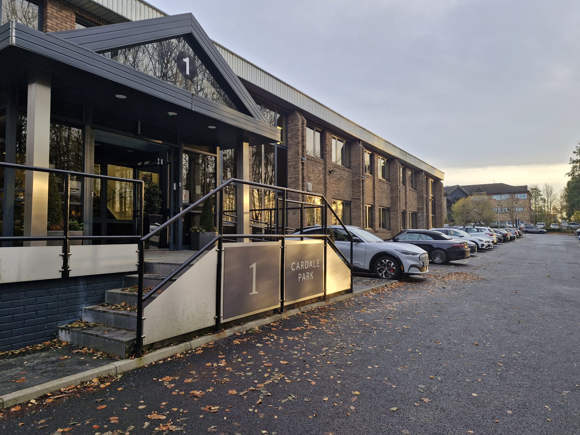 Front entrance of Cardale Park Building 1, with glass doors, dark metal framing, and a ramp leading to the door.